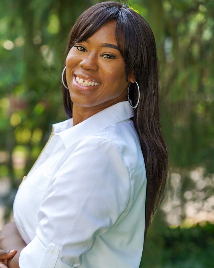 Shanda Deshield smiling outdoors in a white shirt